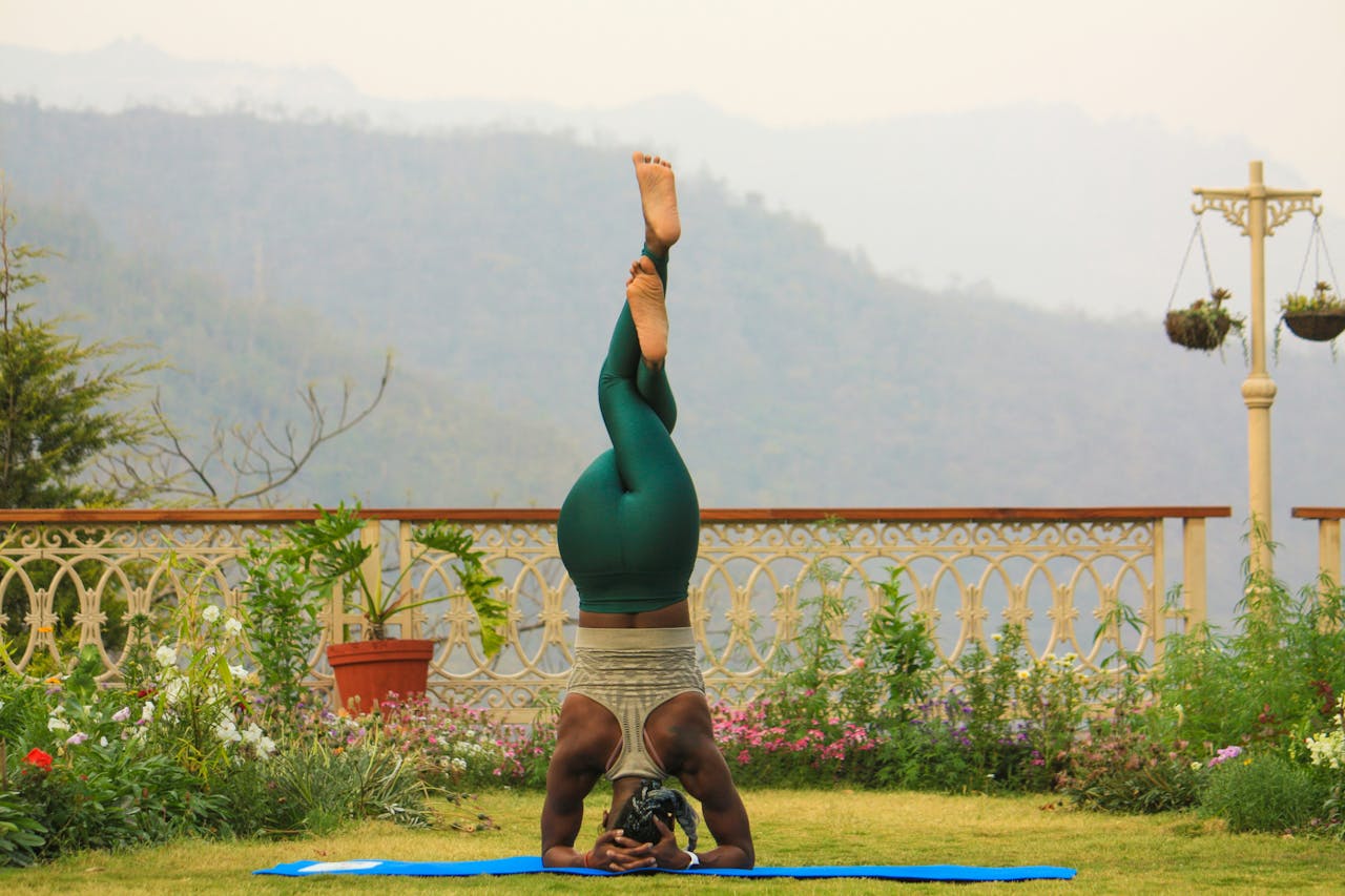 Person practicing yoga headstand outdoors in scenic Rishikesh, India.